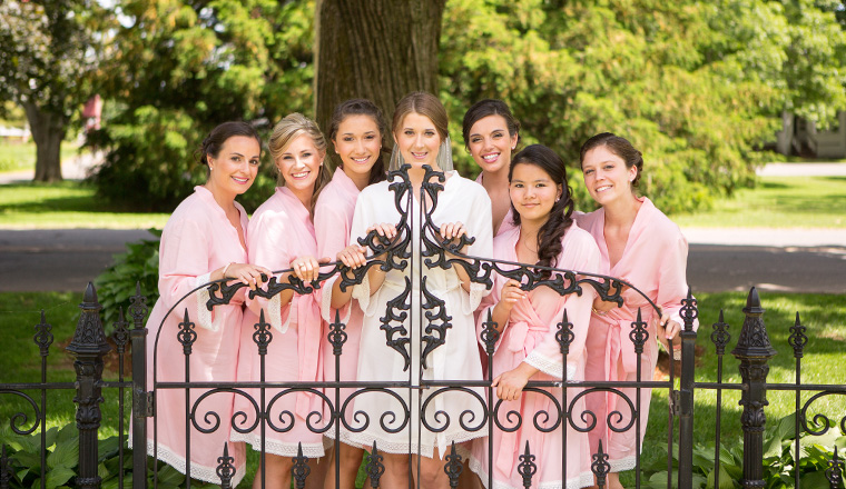 bride and her bridesmaids posing behind a wrought iron fence